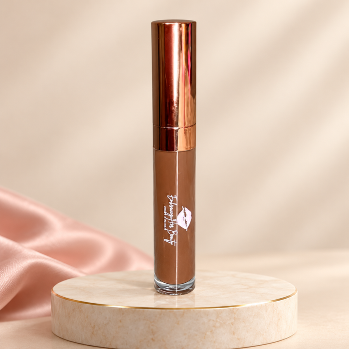 Unshakeable liquid lipstick in its original rose-gold tube on an ivory pedestal with blush satin